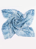 A lightweight square scarf with a blue and white tie-dye shibori pattern, styled in a central swirl on a plain white background.