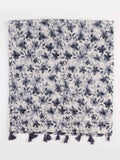 A square scarf with a dense floral and leaf pattern in dark navy blue and gray on a white background, finished with a row of dark tassels along one edge.
